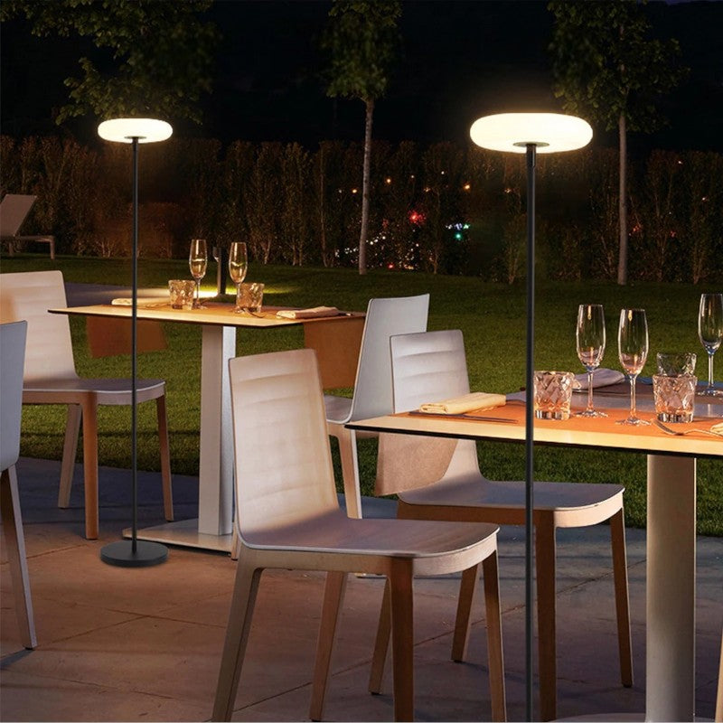 Outdoor solar floor lamp with metal and acrylic body, modern design, stands on patio illuminating with warm LED glow.