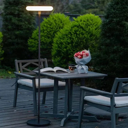 Outdoor solar floor lamp with metal and acrylic body, modern design, stands on patio illuminating with warm LED glow.