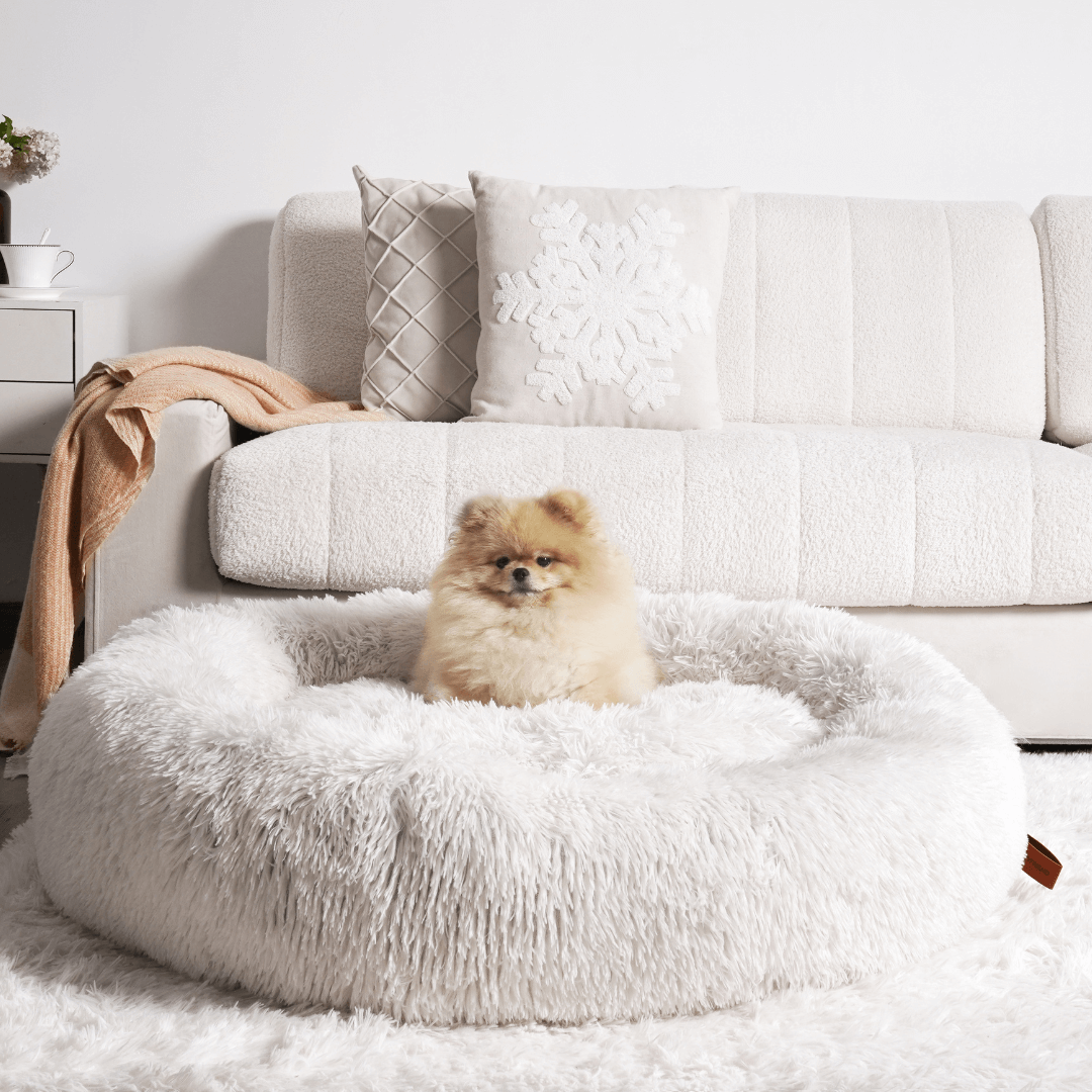 "Plush apricot donut dog bed, anxiety-relieving, round with raised rim, faux fur, for dogs to curl up comfortably."