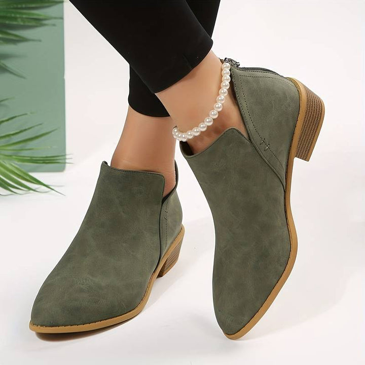 Side view of women's suede ankle boots with low block heel, pointed toe, and back zip, showcasing elegant and chic design.