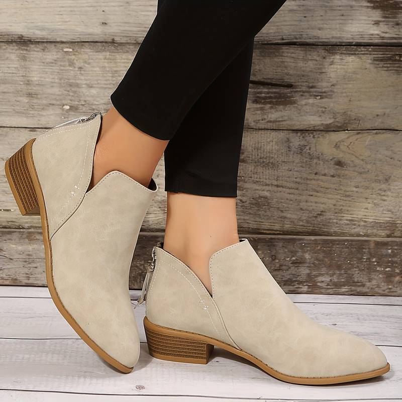 Side view of women's suede ankle boots with low block heel, pointed toe, and back zip, showcasing elegant and chic design.