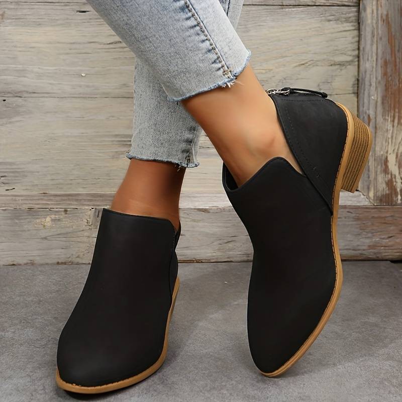 Side view of women's suede ankle boots with low block heel, pointed toe, and back zip, showcasing elegant and chic design.