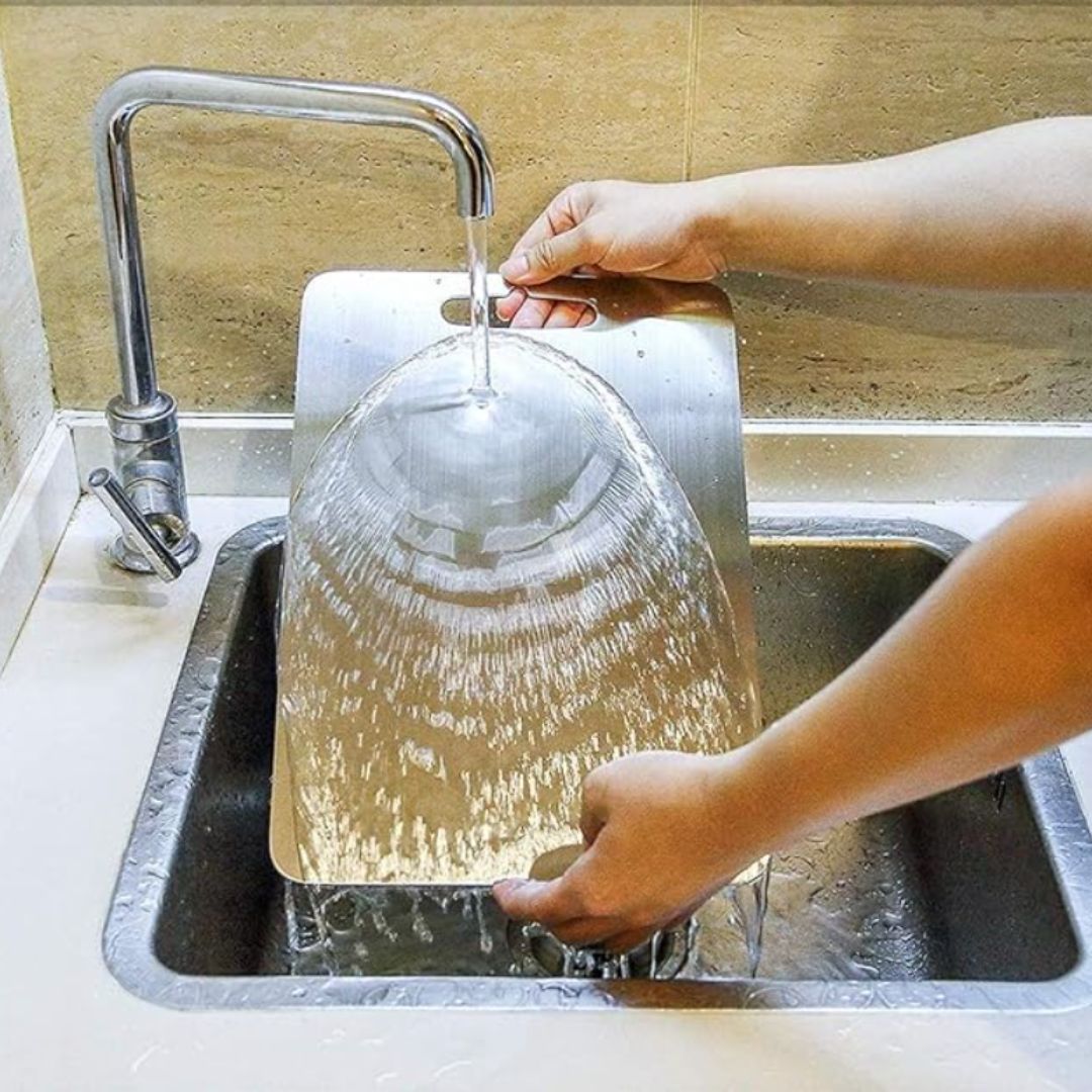 "Sleek stainless steel cutting board in use, showing durability and knife-friendly surface for kitchen prep tasks."