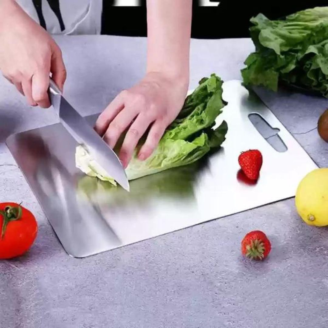 "Sleek stainless steel cutting board in use, showing durability and knife-friendly surface for kitchen prep tasks."