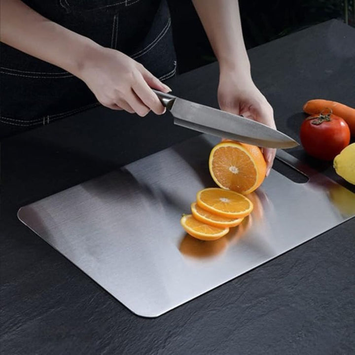 "Sleek stainless steel cutting board in use, showing durability and knife-friendly surface for kitchen prep tasks."