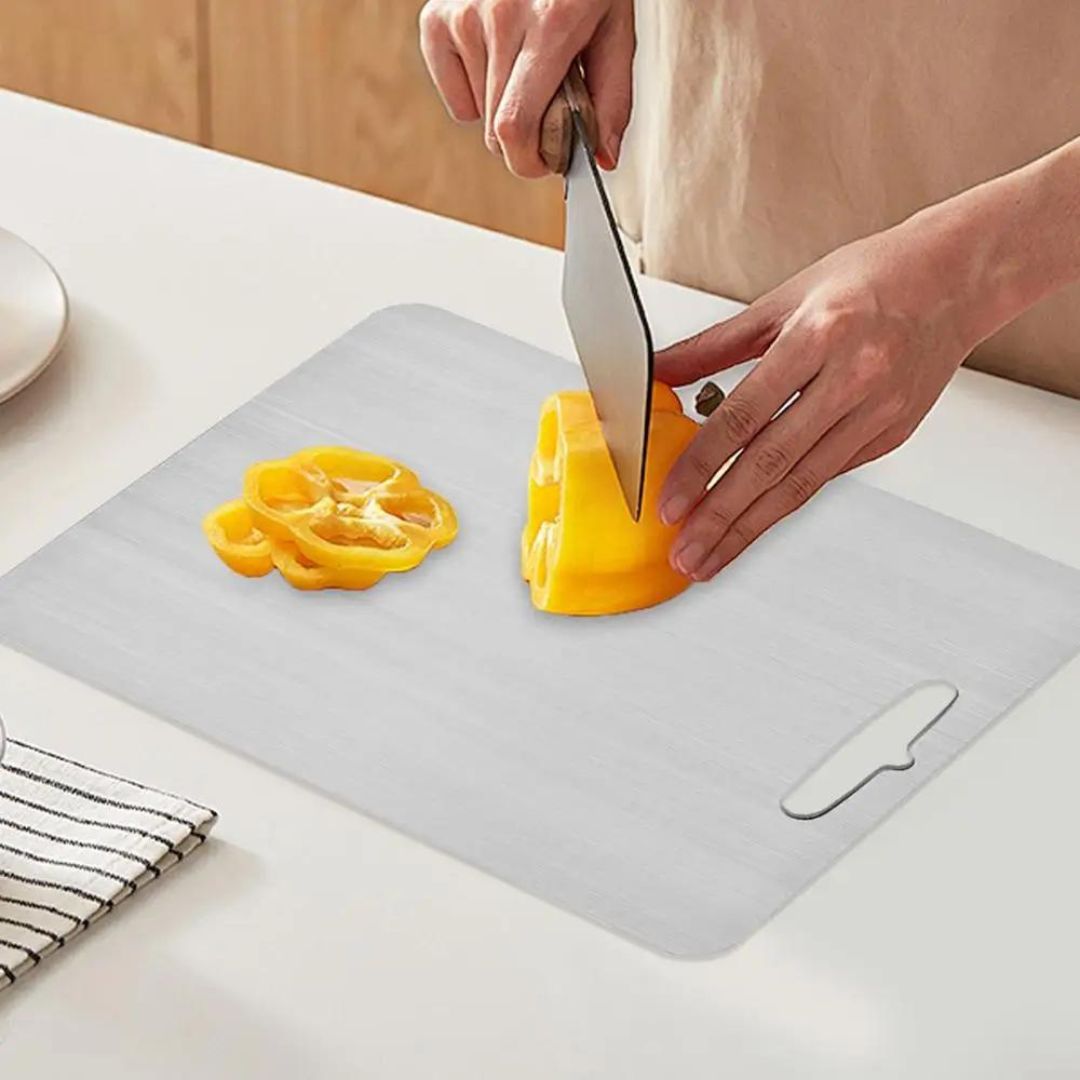 "Sleek stainless steel cutting board in use, showing durability and knife-friendly surface for kitchen prep tasks."