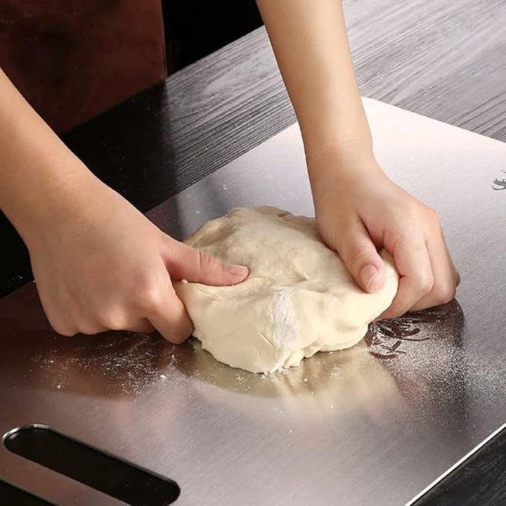 "Sleek stainless steel cutting board in use, showing durability and knife-friendly surface for kitchen prep tasks."