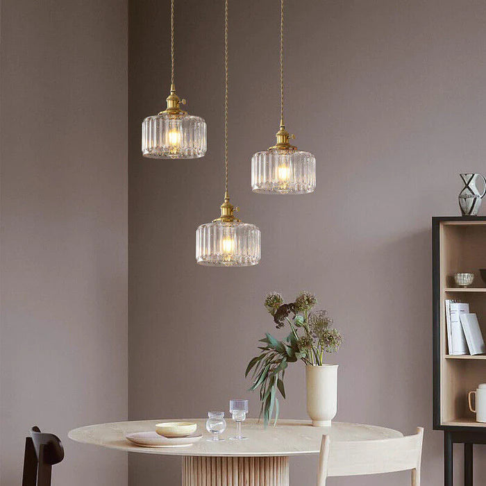 Vintage cylindrical glass pendant lamp casting warm glow; elegant centerpiece for home decor. Perfect for living and dining a