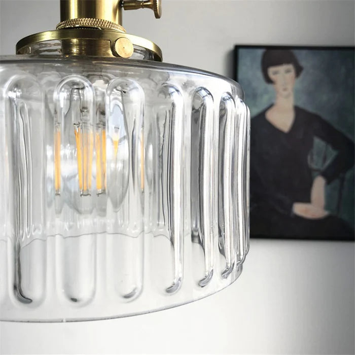 Vintage cylindrical glass pendant lamp casting warm glow; elegant centerpiece for home decor. Perfect for living and dining a