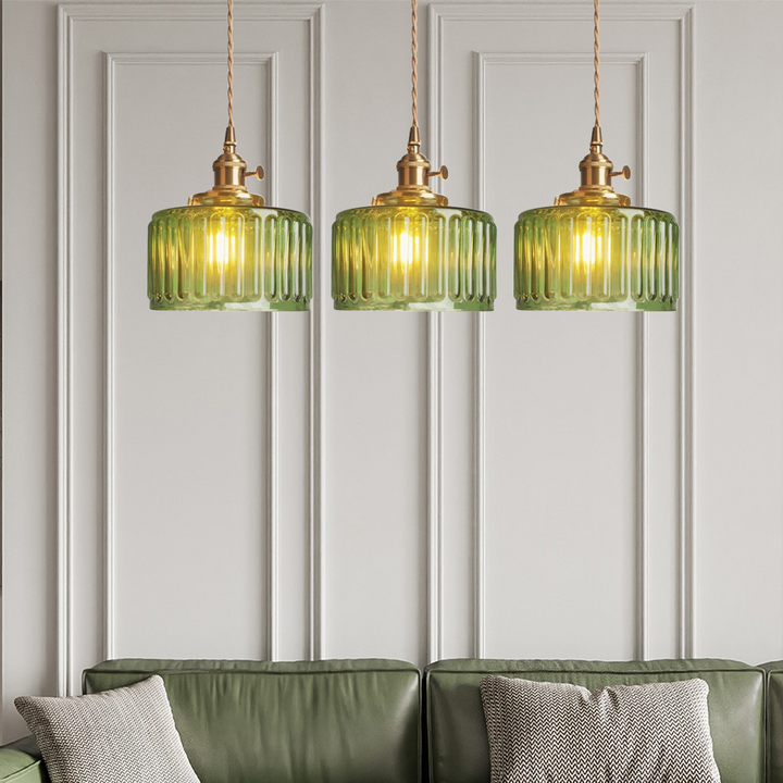 Vintage cylindrical glass pendant lamp casting warm glow; elegant centerpiece for home decor. Perfect for living and dining a