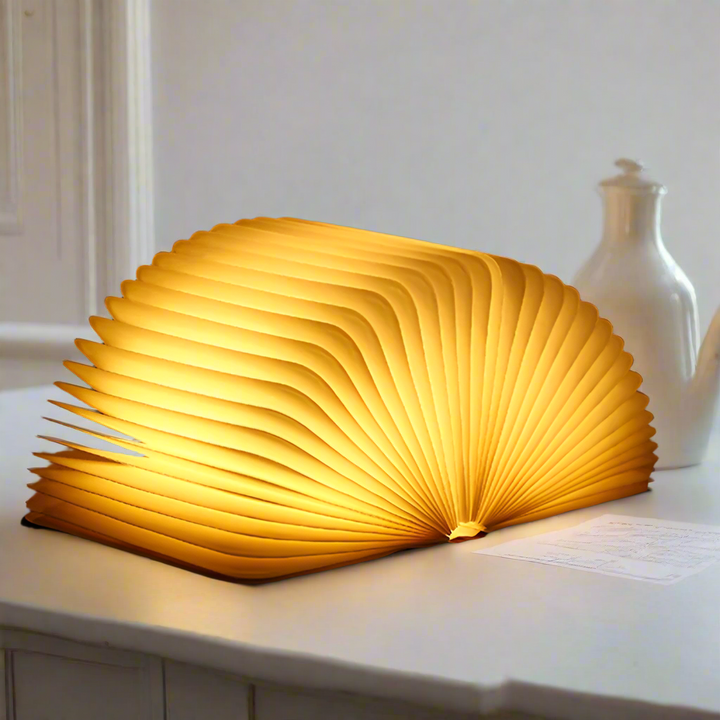 "Whimsical LED book lamp with warm glow, resembling an open book, perfect for cozy decor in bedrooms or study areas."