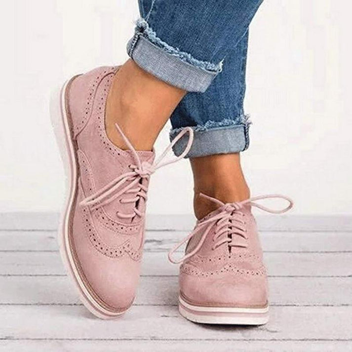 Women's lace-up brogue trainers with flat sole, featuring classic design and secure closure for elegant, comfortable wear.