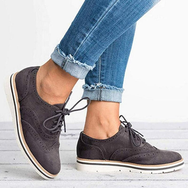Women's lace-up brogue trainers with flat sole, featuring classic design and secure closure for elegant, comfortable wear.