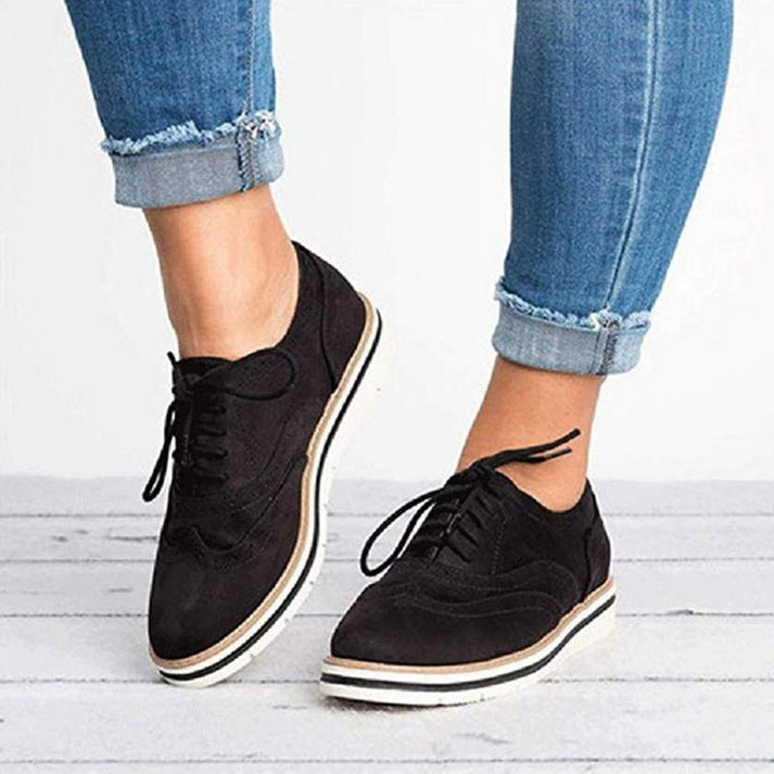 Women's lace-up brogue trainers with flat sole, featuring classic design and secure closure for elegant, comfortable wear.