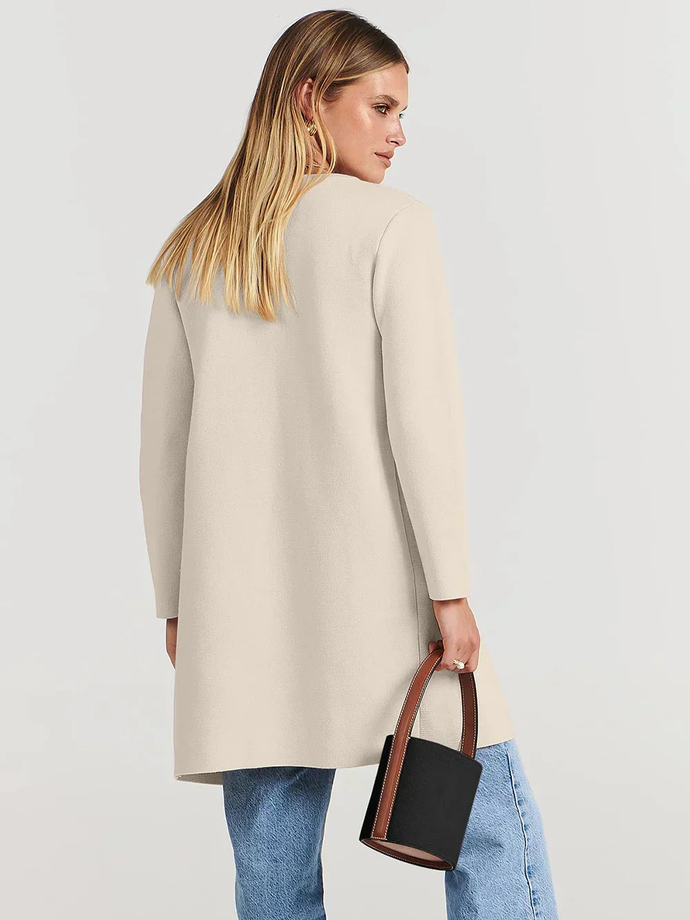 "Women's wool blend knee-length coat with wide lapel and patch pockets, showcasing a relaxed fit and minimalist design."