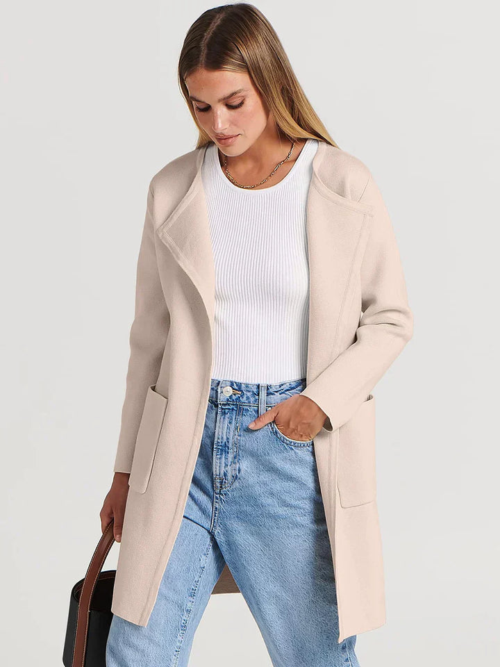 "Women's wool blend knee-length coat with wide lapel and patch pockets, showcasing a relaxed fit and minimalist design."