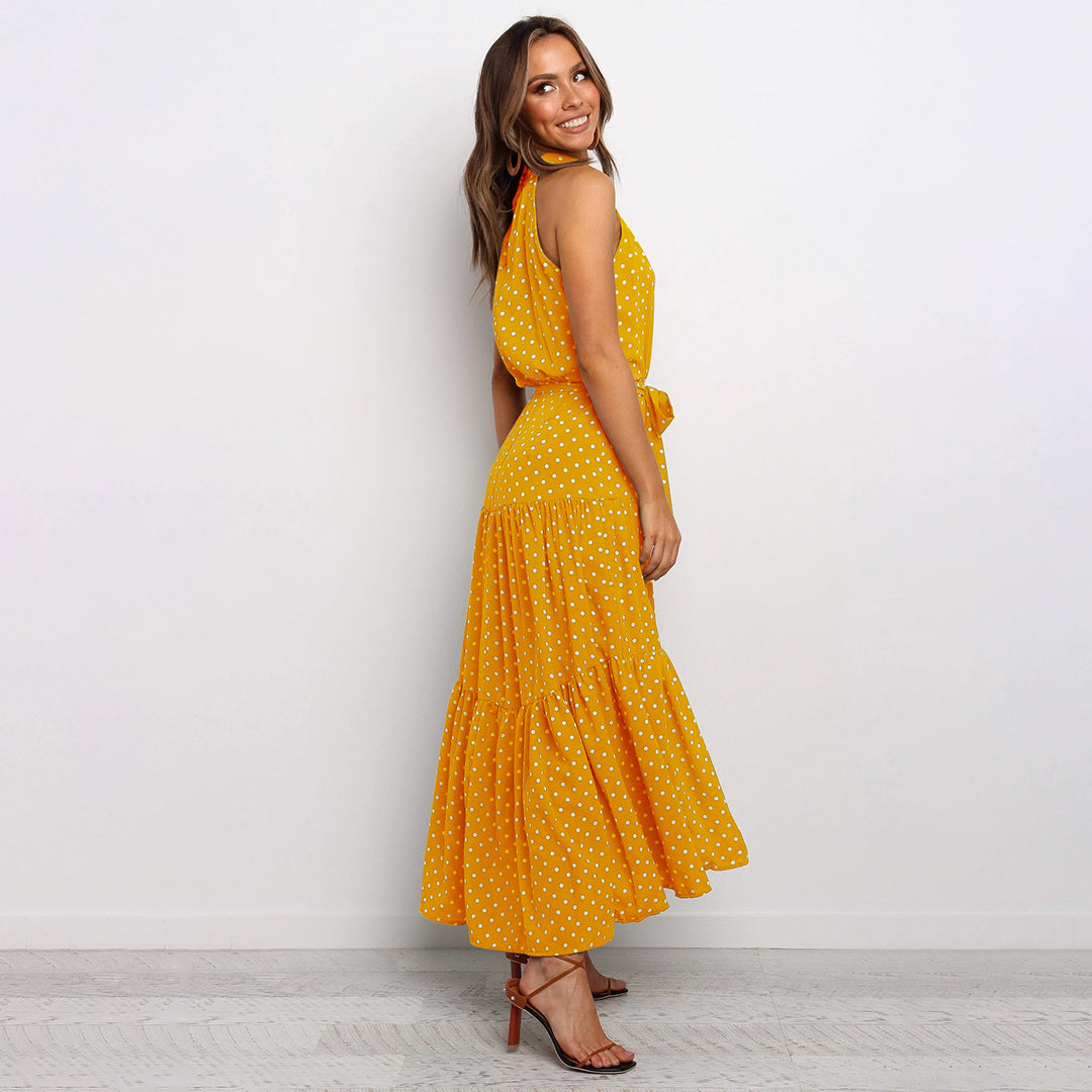 "Women's Yellow Polka Dot Halter Neck Maxi Dress with Tie Waist, featuring a tiered skirt for a flowing, elegant look."